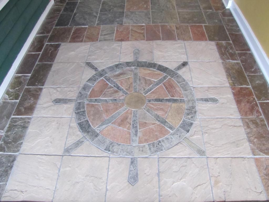 Decoratief stenen vloermozaïek met een cirkelvormig kompasachtig ontwerp in een gang.