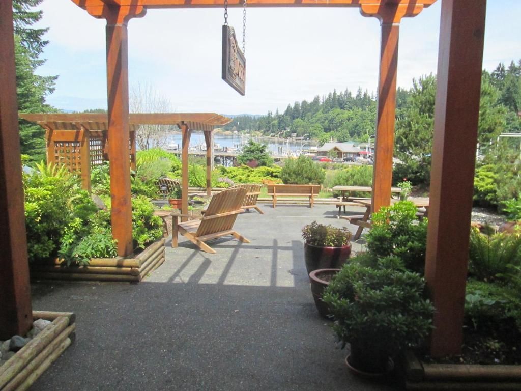Houten pergola met uitzicht op een tuinterras met stoelen, potplanten en een schilderachtig uitzicht over de vallei.