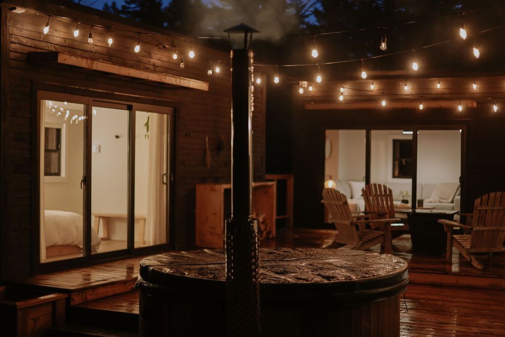 Gezellig terras met lichtslingers, houten vlonder, ronde tafel en stoelen 's avonds.