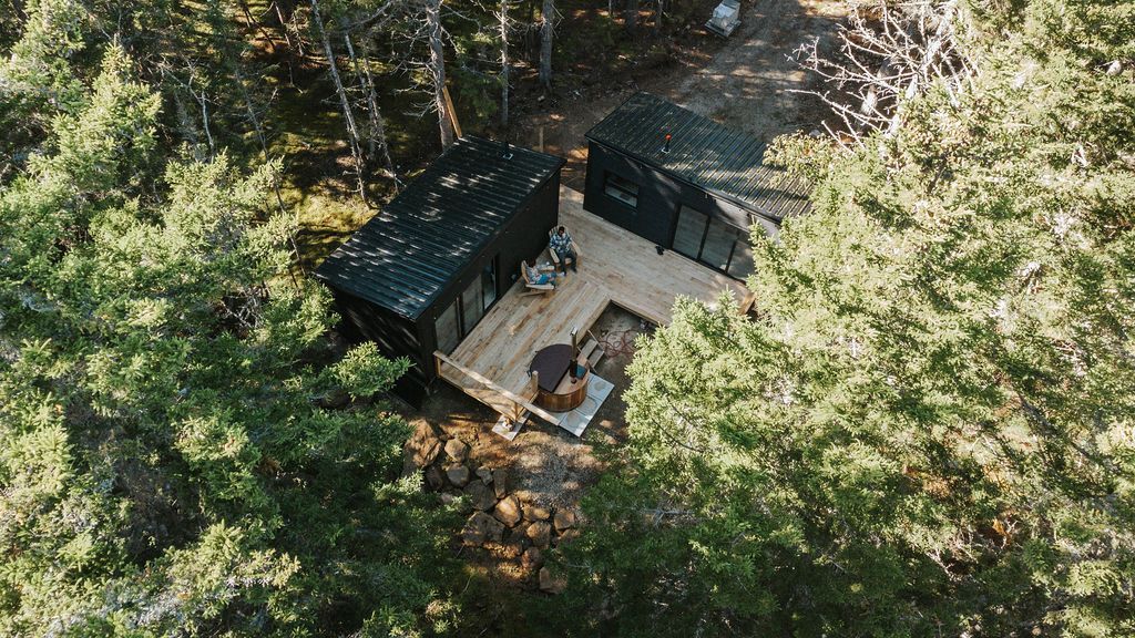 Luchtfoto van een kleine hut met een terras, verscholen in een dicht groen bos.