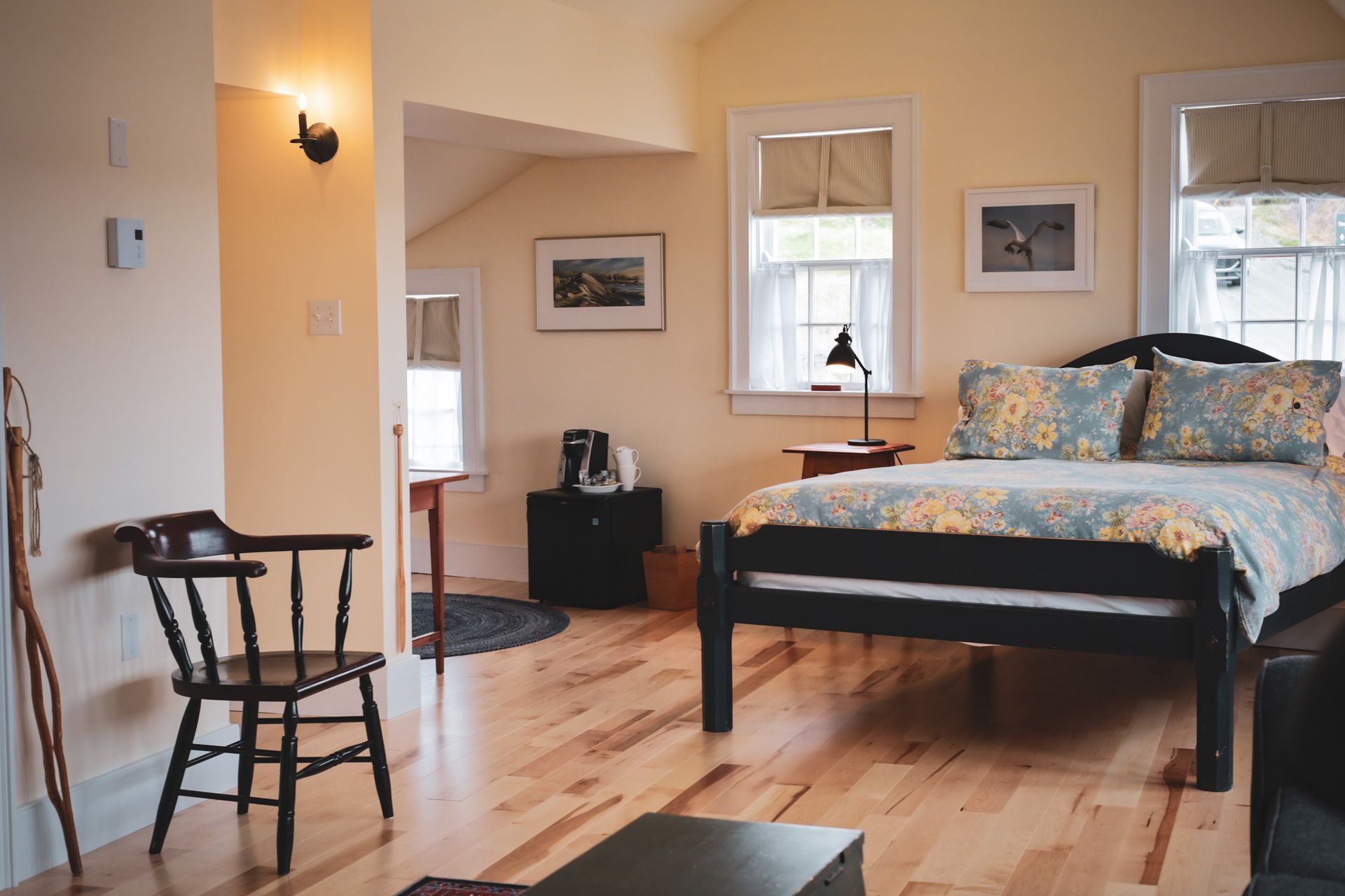 Lichte slaapkamer van Fisher's Loft Inn in Port Rexton met houten bed, twee ramen, houten vloer en een klein bureau tegen de muur.