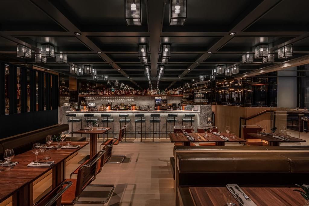 Leeg, modern restaurantinterieur van Hôtel Le Germain Montréal met warme verlichting, houten tafels en een lange centrale gang.