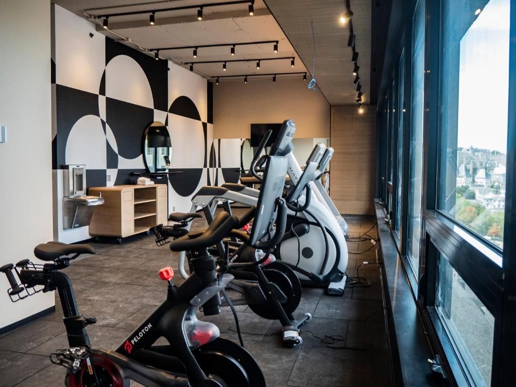 Moderne sportschool van Hôtel Le Germain Montréal met hometrainers, loopbanden en ramen van vloer tot plafond met uitzicht over de stad.