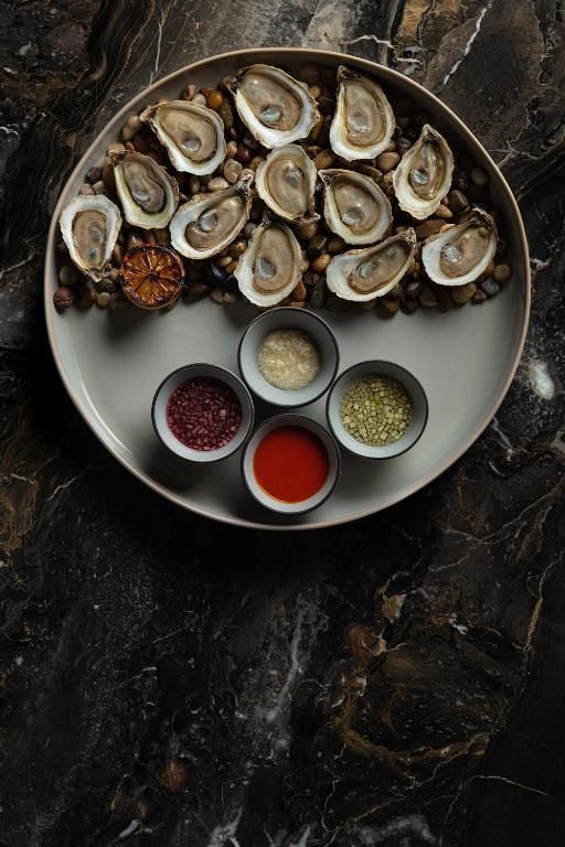 Oesters op ijs met citroen, sauzen en kruiden op een donkere marmeren tafel van Hôtel Le Germain Montréal.