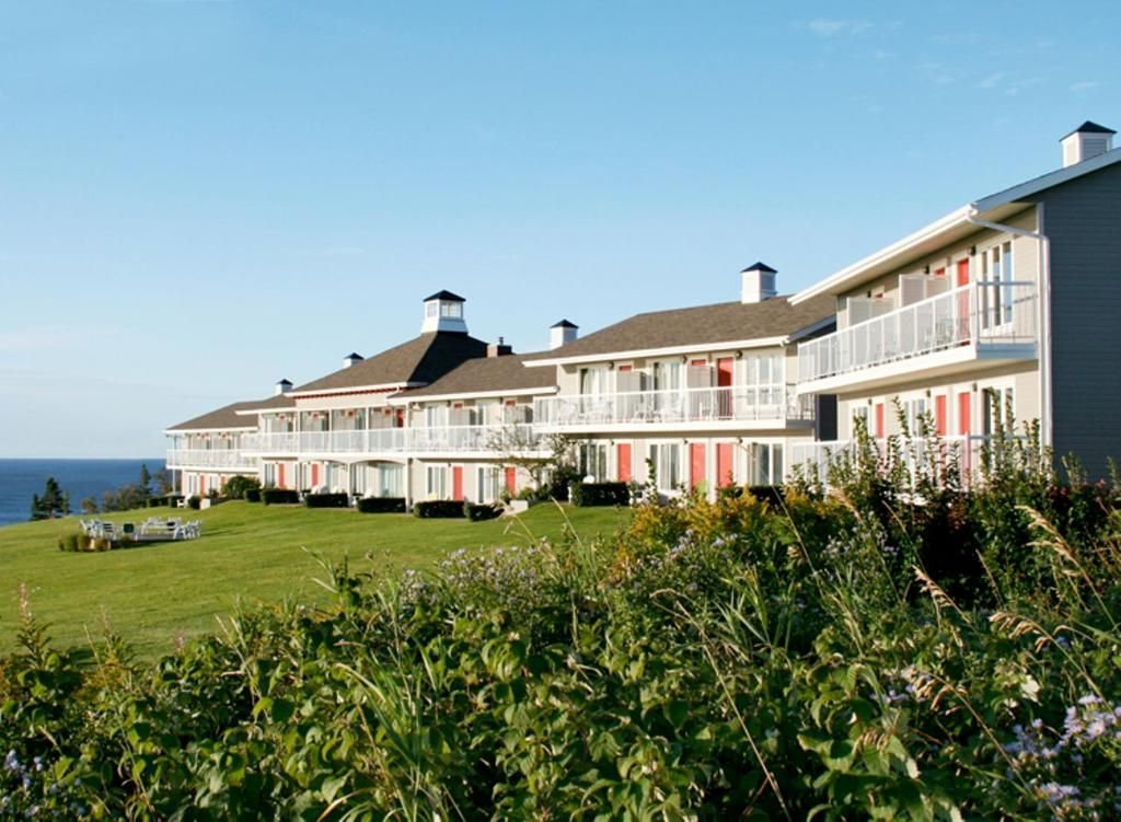 Uitizicht op Hotel Le Mirage aan de kust met uitzicht op een met gras begroeide klif aan zee onder een heldere hemel.