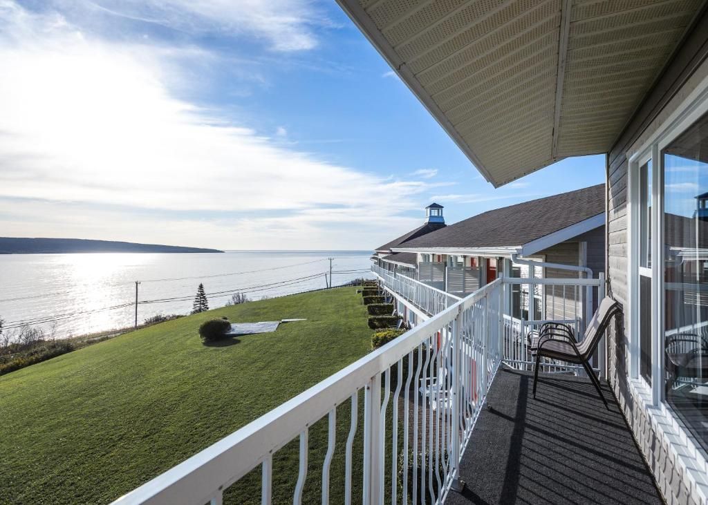 Balkon van Hotel Le Mirage met uitzicht op een rustig gazon aan het water, met witte balustrades en een heldere hemel bij zonsondergang.
