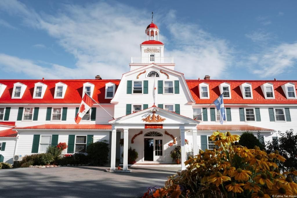 Hotel Tadoussac met rood dak en centrale toren onder een blauwe hemel.