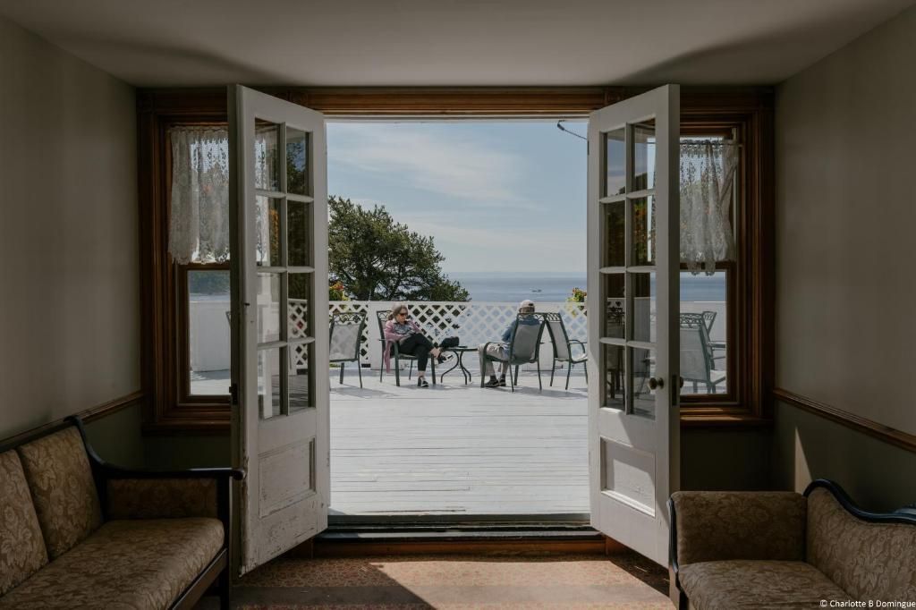 Openslaande Franse deuren van Hotel Tadoussac geven toegang tot een terras aan zee met stoelen en uitzicht op de oceaan.