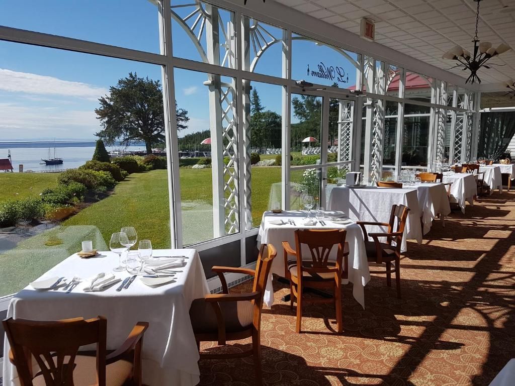 Restaurant van Hotel Tadoussac aan het water met tafels en stoelen met witte tafelkleden en grote ramen met uitzicht op zee.