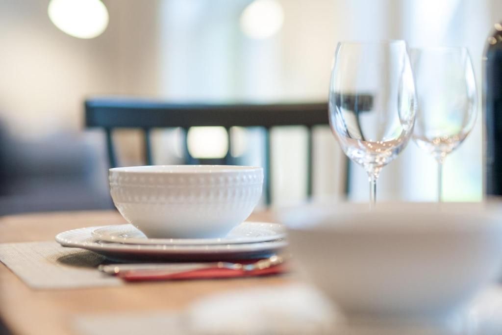 Dek de tafel met witte kommen, borden en wijnglazen in een sfeervol verlichte eetkamer.
