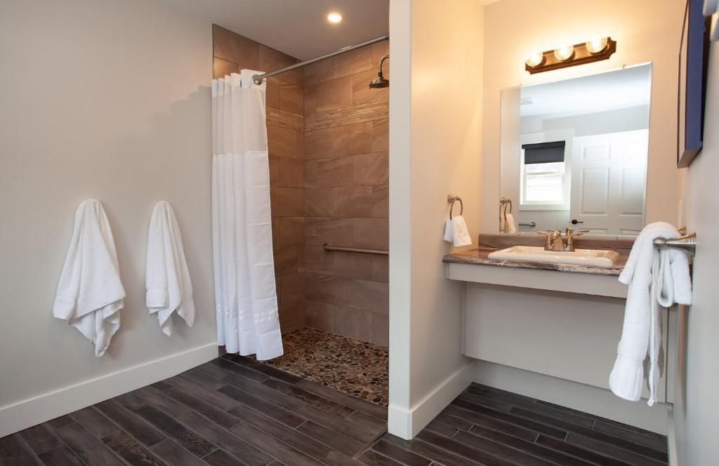Moderne badkamer met inloopdouche, wastafelmeubel en witte handdoeken aan de muur.
