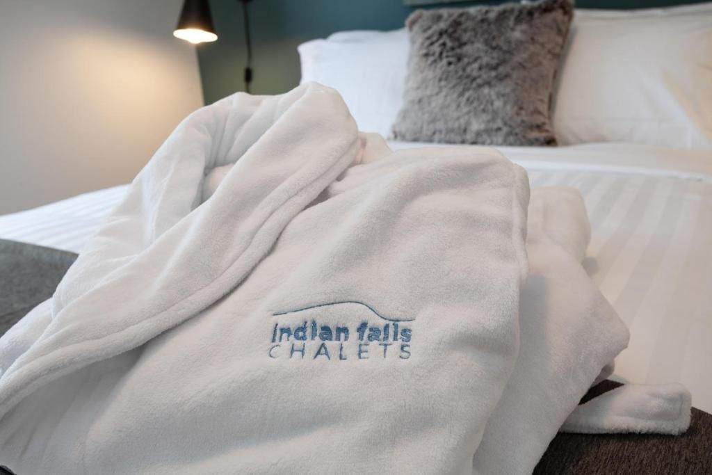 Een witte badjas op een bed in een sfeervol verlichte hotelkamer, met een zichtbaar logo van