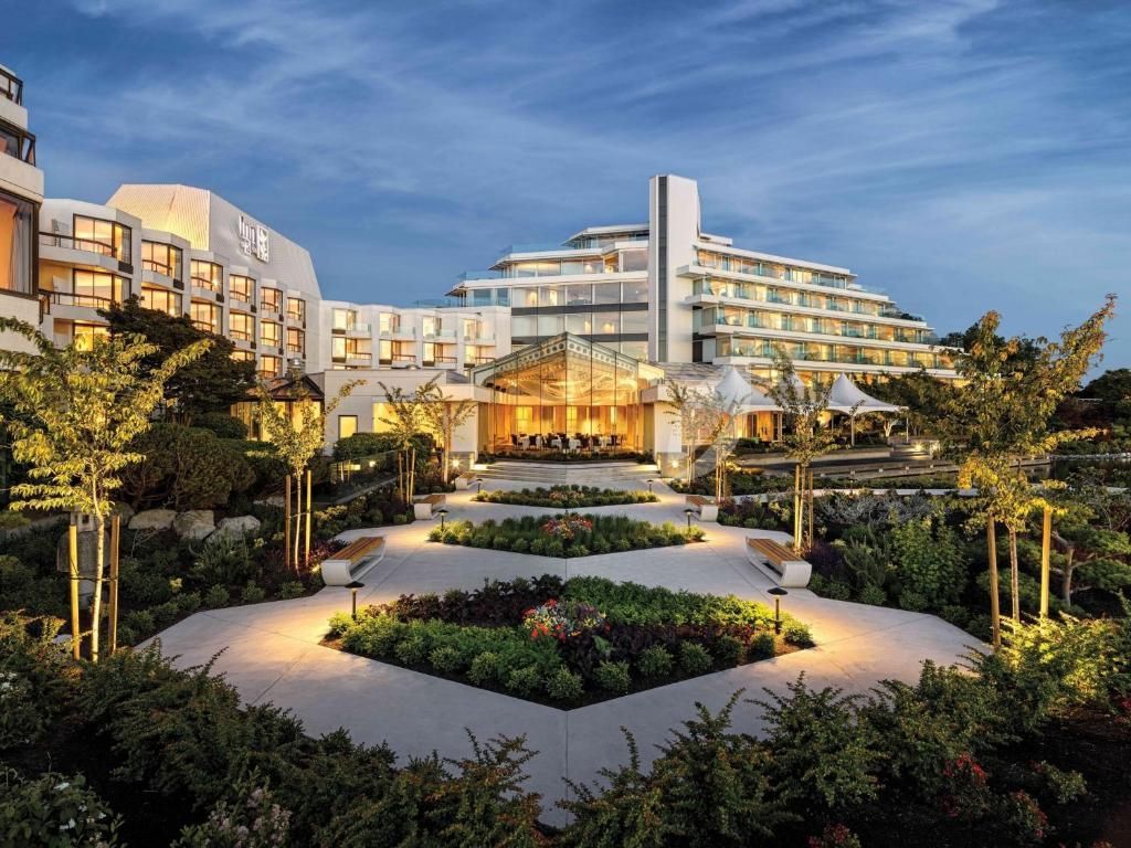 Verlichte binnenplaats van een luxe resort met aangelegde tuinen en moderne gebouwen bij schemering.