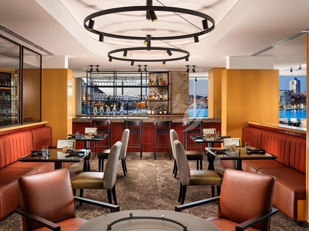 Stijlvolle loungebar met rode banken, leren stoelen en ronde plafondlampen.