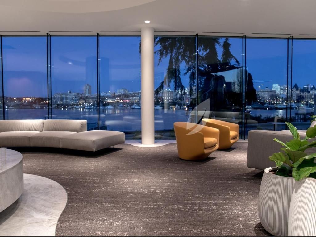 Moderne lounge met gebogen bank en stoelen, met uitzicht op de skyline van de stad 's nachts door kamerhoge ramen.
