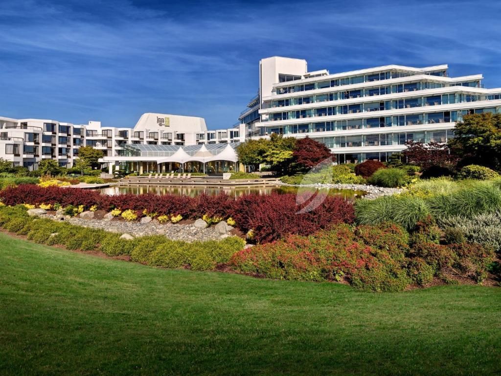 Modern hotelresort met witte gebouwen, aangelegde bloemperken en een groen gazon onder een blauwe hemel.