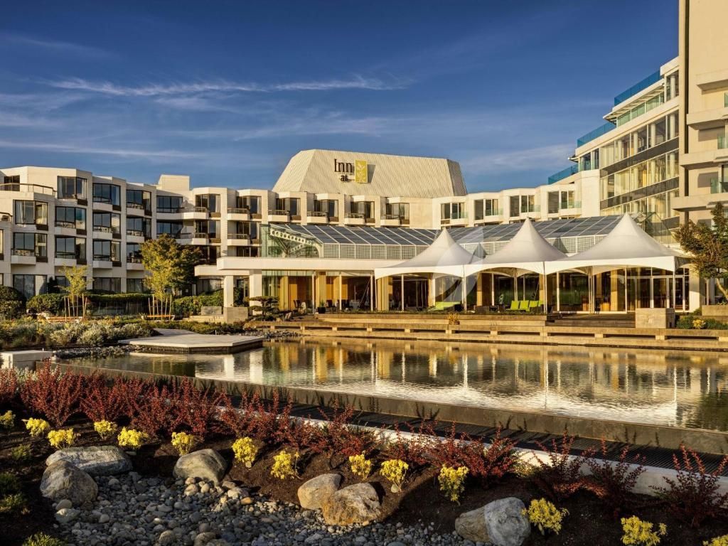 Modern hotelresort met witte overdekte terrassen, een spiegelvijver en aangelegde tuinen bij zonsondergang.