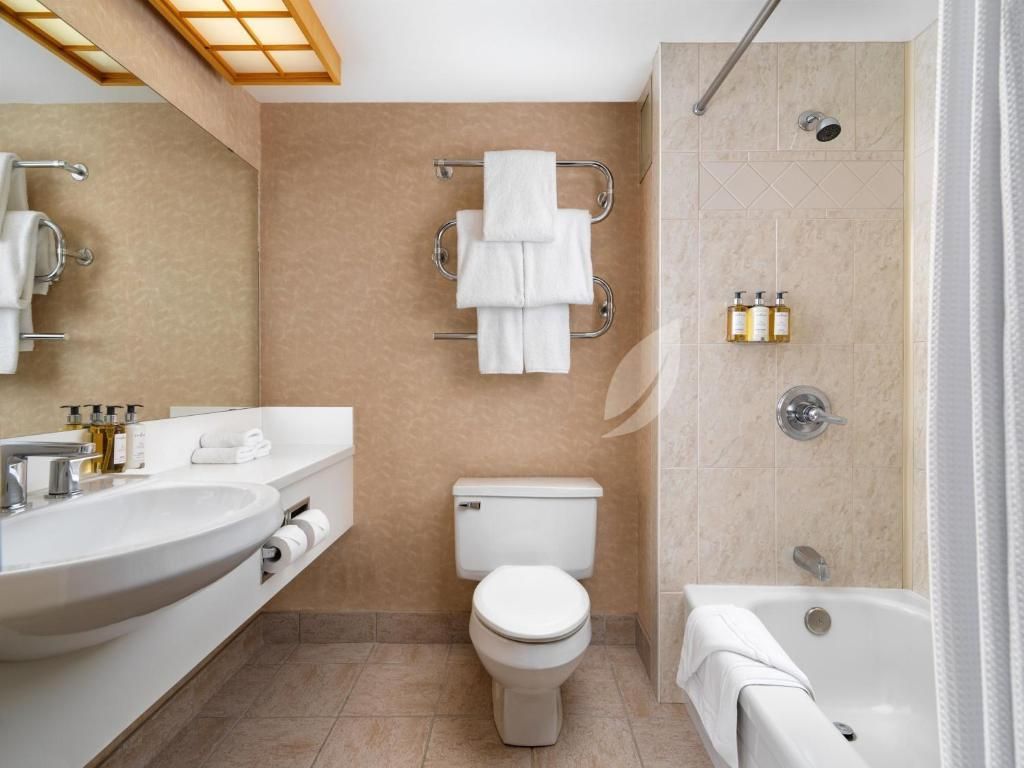 Compacte beige badkamer met wastafel, toilet, badkuip en douchecabine.