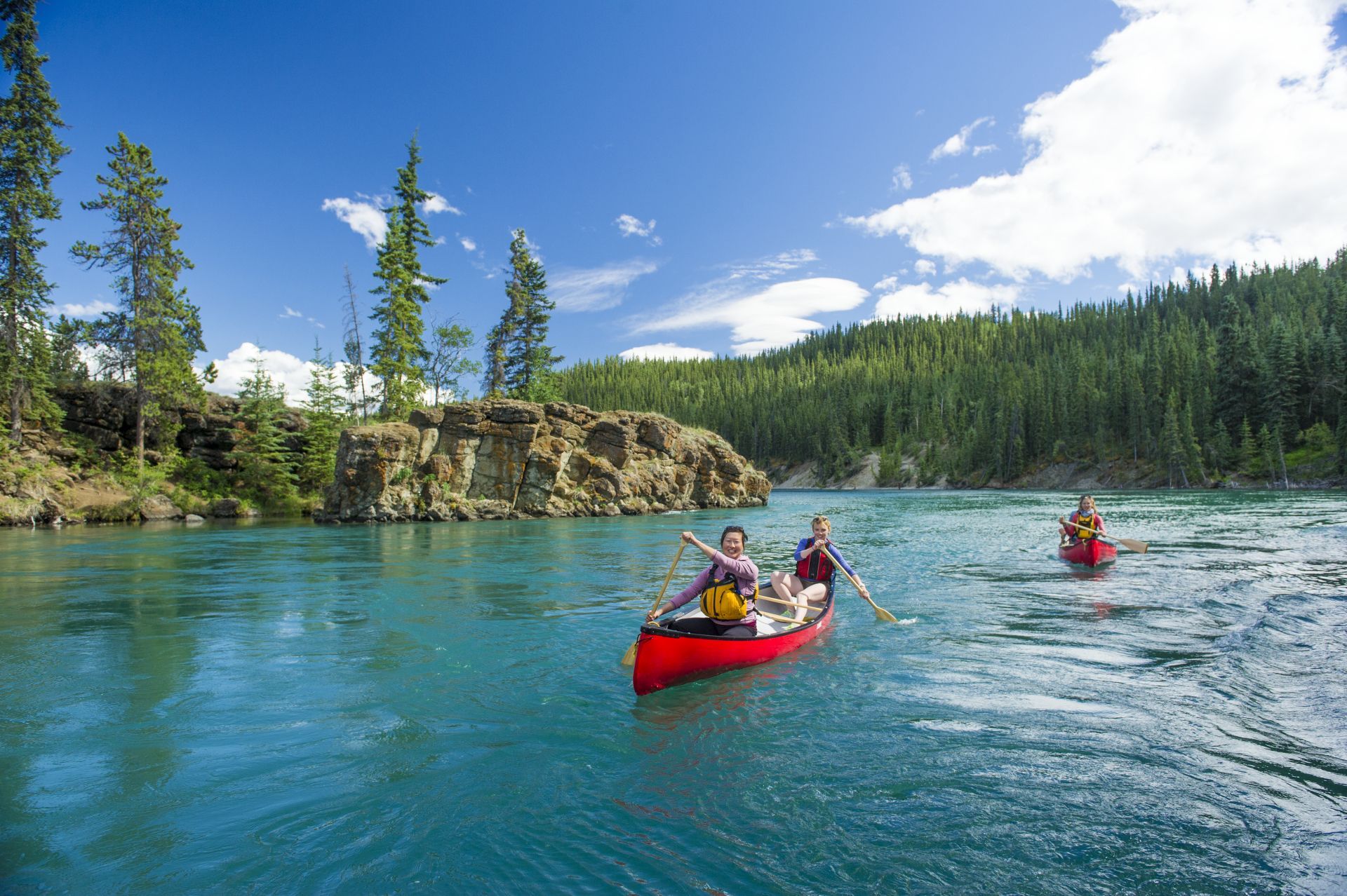 © Government of Yukon Twee mensen die in kano's over de Yukon River bij Miles Canyon meer peddelen