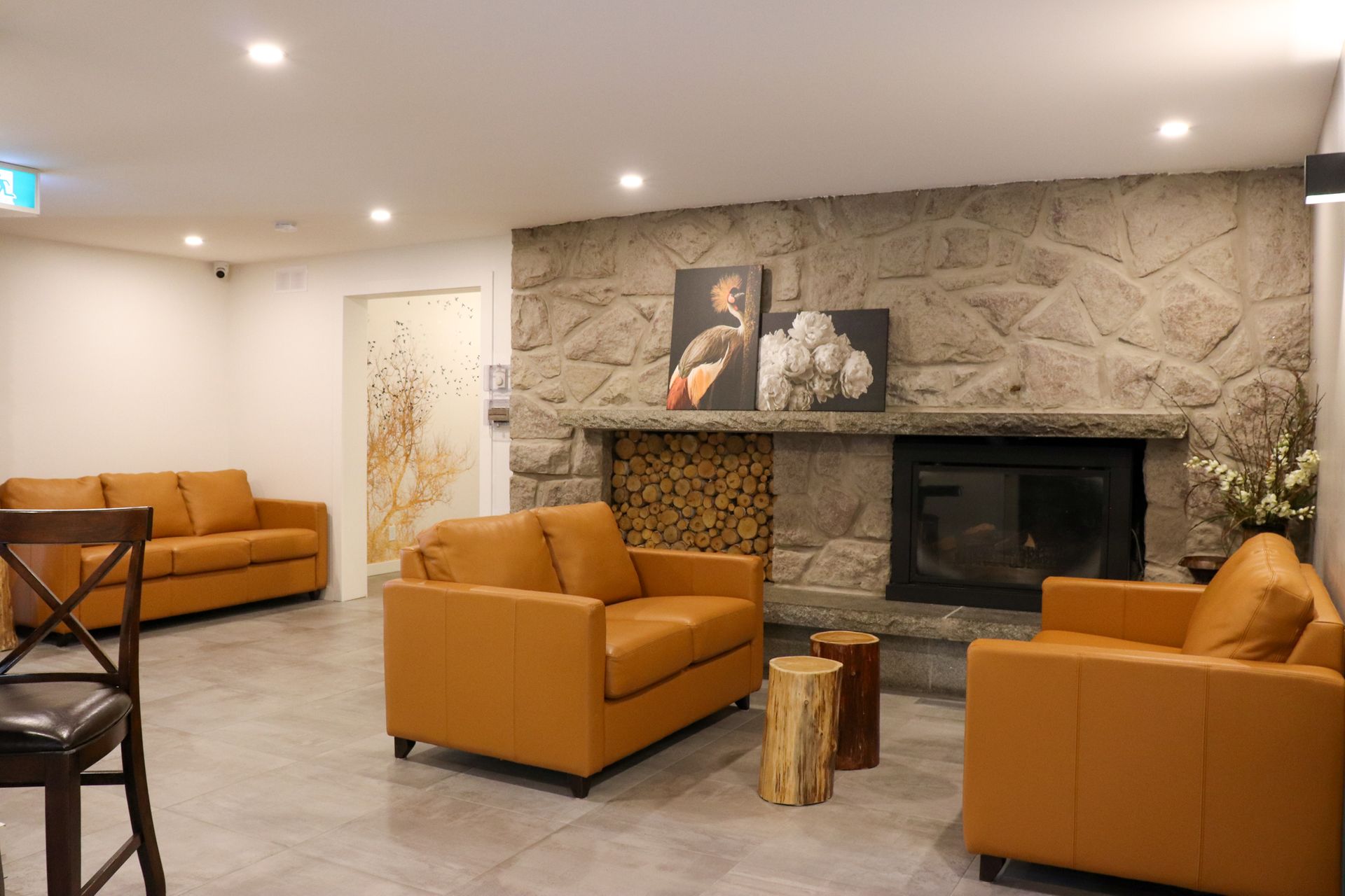 Moderne woonkamer met beige banken, stenen open haard en ingelijste kunstwerken aan de muur.