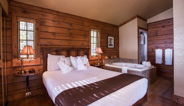 Rustieke houten slaapkamer met twee bedden, warme lampen en een gezellig interieur in hutstijl.