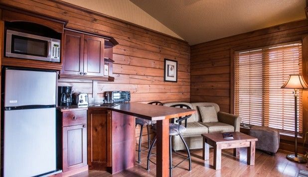 Gezellige studio met houten lambrisering, kitchenette, bank, salontafel en raamjaloezieën.