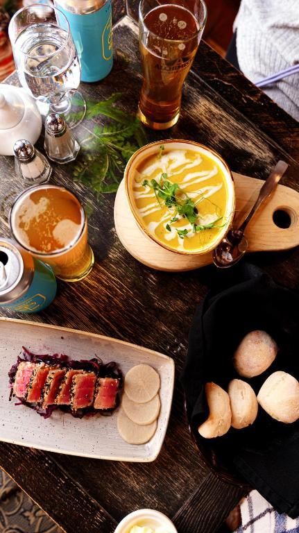 Een uitgebreid brunchbuffet met soep, bier, wijn, brood en een maaltijd geserveerd op een rustieke houten tafel.