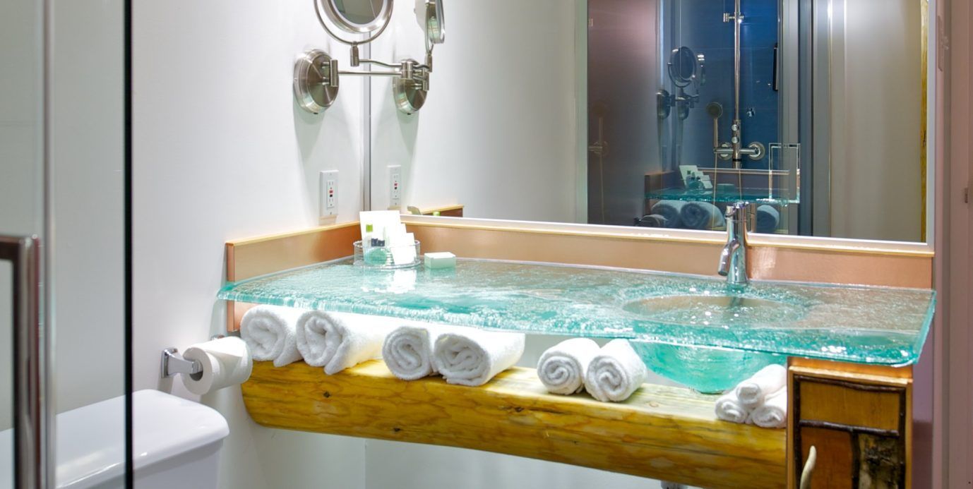 Moderne badkamer met een houten jacuzzi gevuld met water en opgerolde witte handdoeken aan de rand.