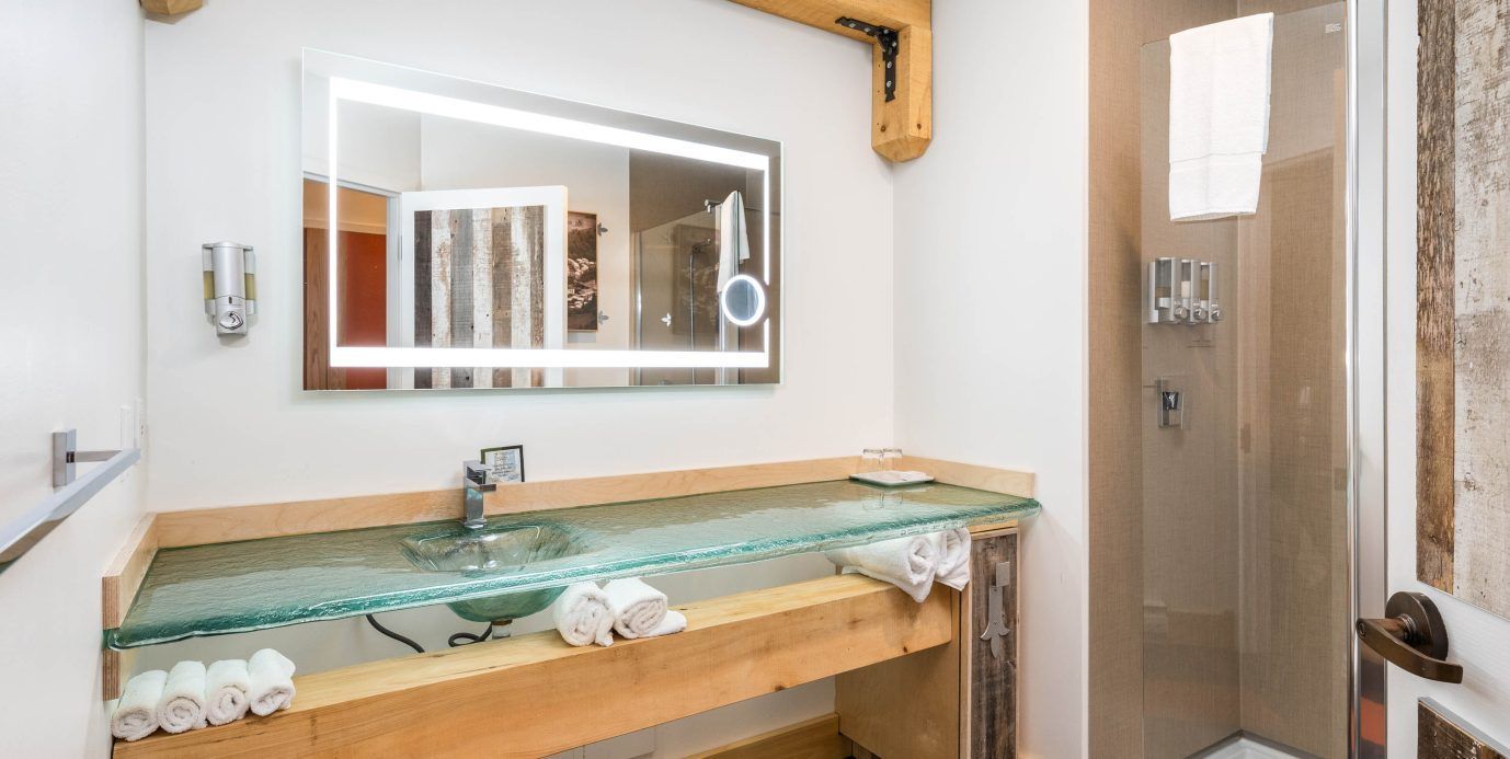 Moderne badkamerkast met glazen wastafel, spiegelkastje en inloopdouche aan de rechterkant.