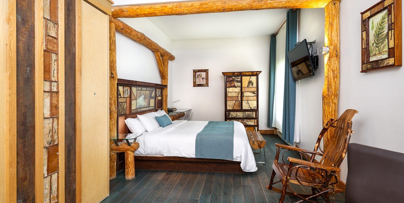 Gezellige slaapkamer met een hemelbed, houten stoel, tv aan de muur en rustieke decoratie.