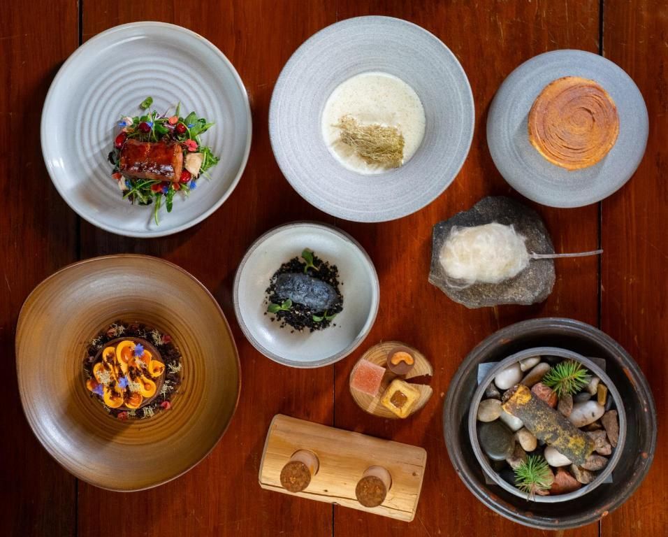 Diverse schalen en kommen op borden, uitgestald op een houten tafel, tonen een meergangenmenu.