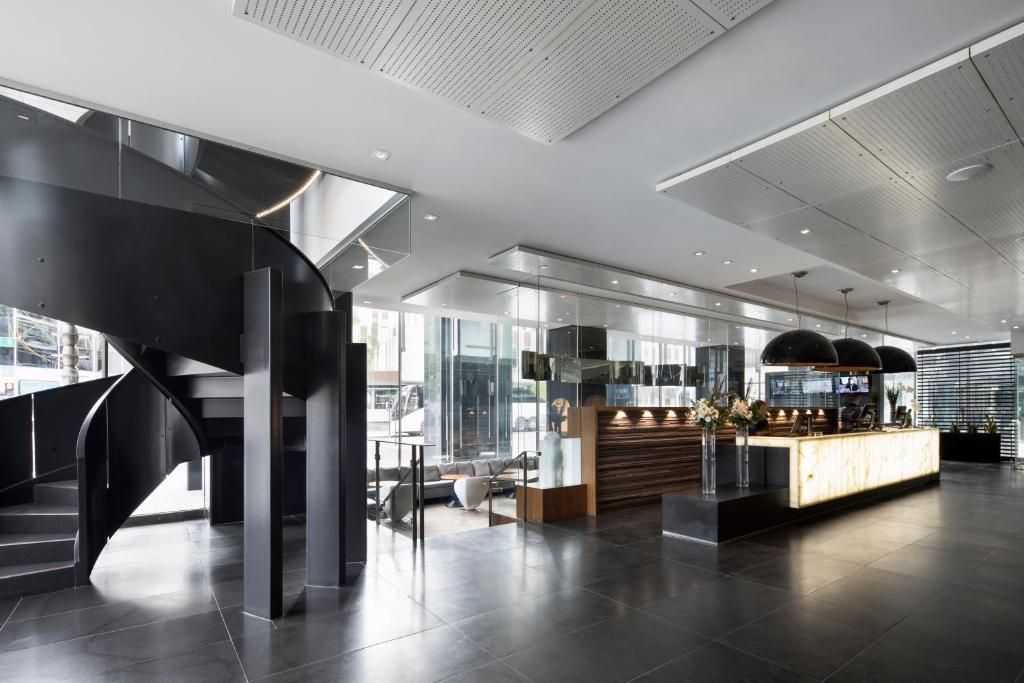 Modern lobby-interieur met zwarte wenteltrap, glazen wanden en een lange bar of receptiebalie.