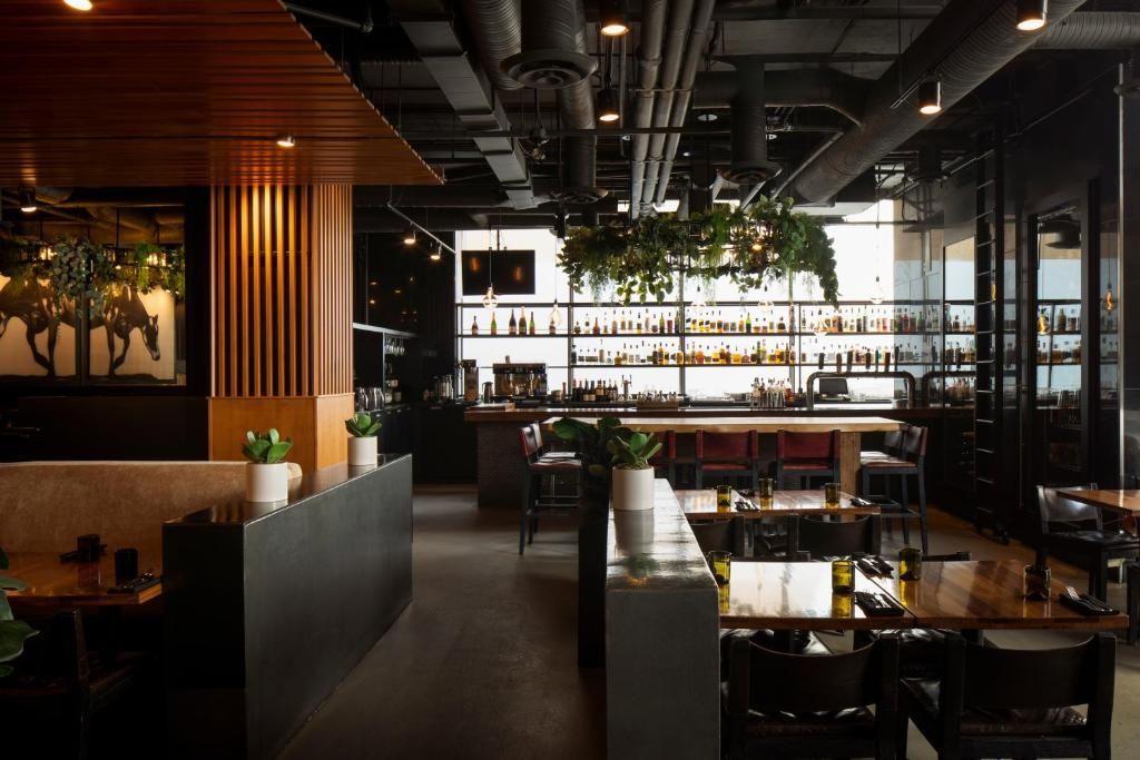 Een sfeervol, modern restaurantinterieur met houten accenten, barplanken en lege tafels en stoelen.