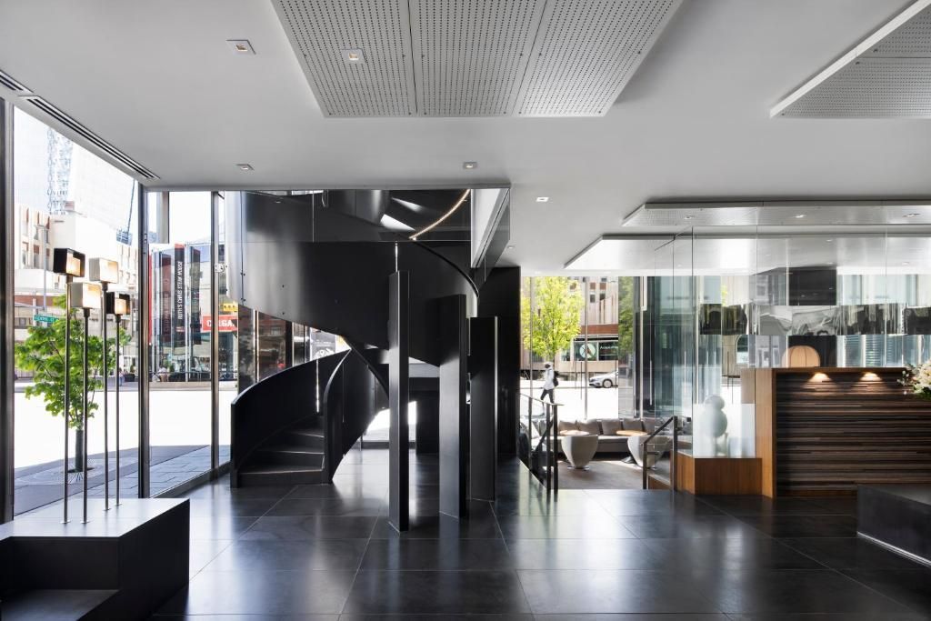 Moderne lobby met zwarte wenteltrap, glazen wanden en receptiebalie.