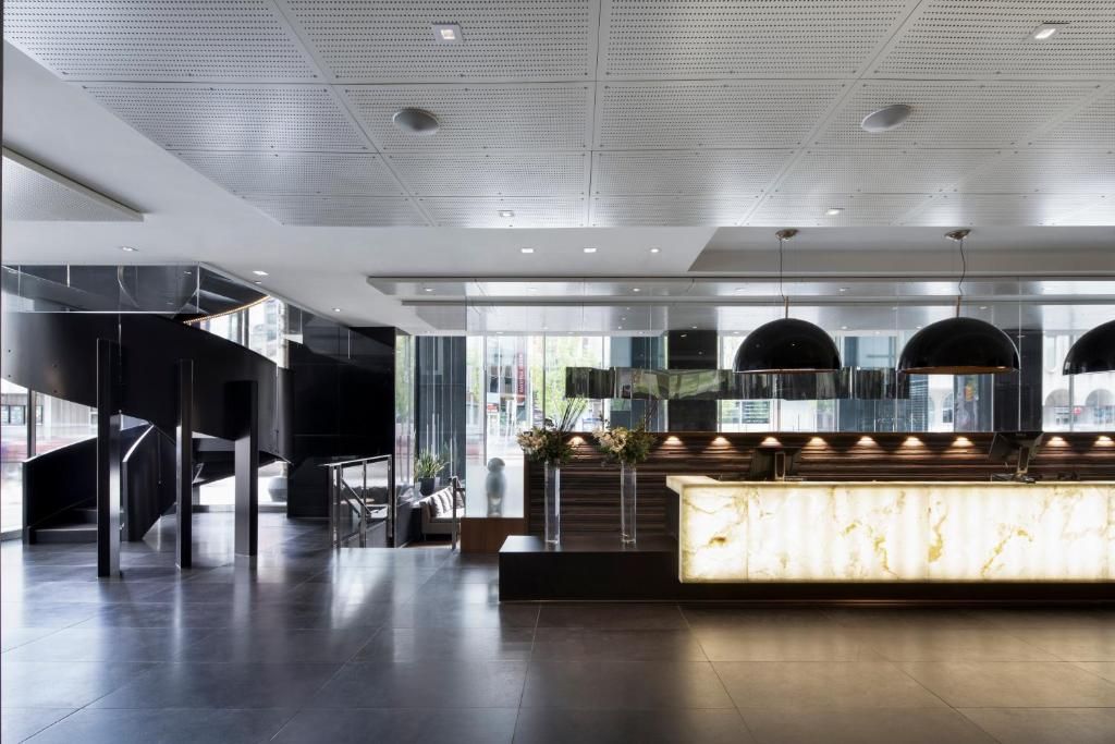 Moderne hotellobby met glanzende vloeren, een verlichte receptie en zwarte loungestoelen.