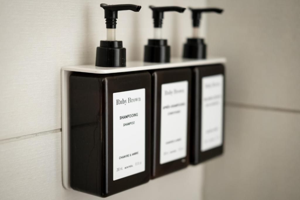 Drie zwarte zeepdispensers met pompje, naast elkaar aan de muur gemonteerd.
