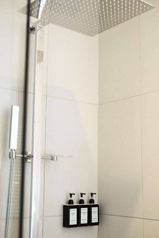 Moderne douche met glazen scheidingswand, regendouchekop en aan de muur gemonteerde zeepdispensers.