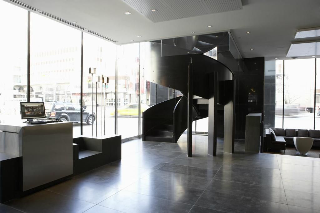Moderne lobby met grote ramen, een zwarte wenteltrap en strakke, minimalistische zitmeubelen.