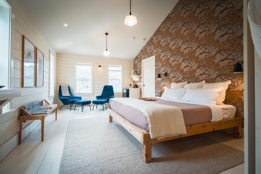 Moderne slaapkamer met een accentmuur van natuursteen, blauwe stoelen en een zithoek bij het raam.