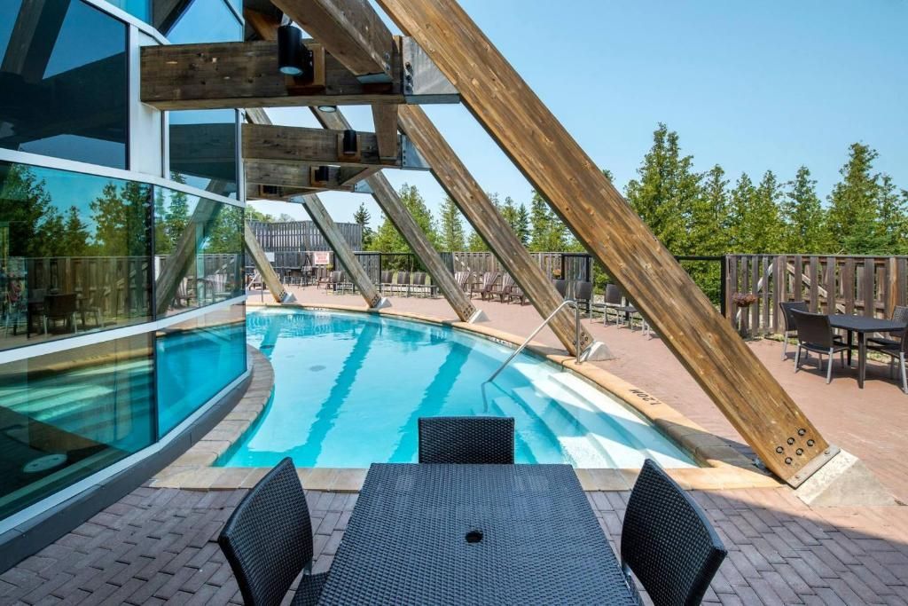 Modern terras bij het zwembad met ligstoelen, turquoise zwembad en houten pergola.