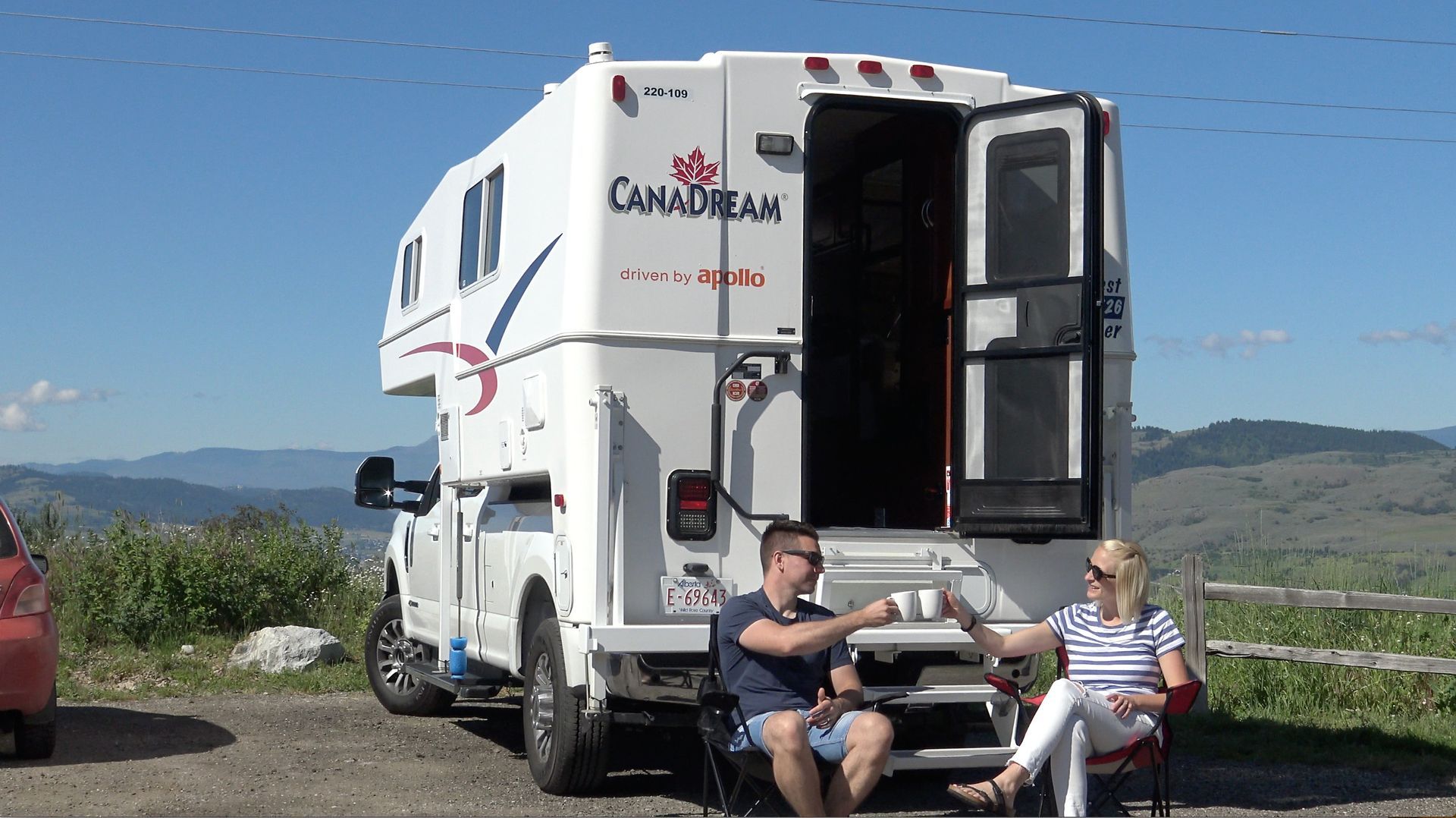 Maxi Travel 4x4 Camper geparkeerd op een schilderachtig uitkijkpunt, met twee mensen die buiten zitten