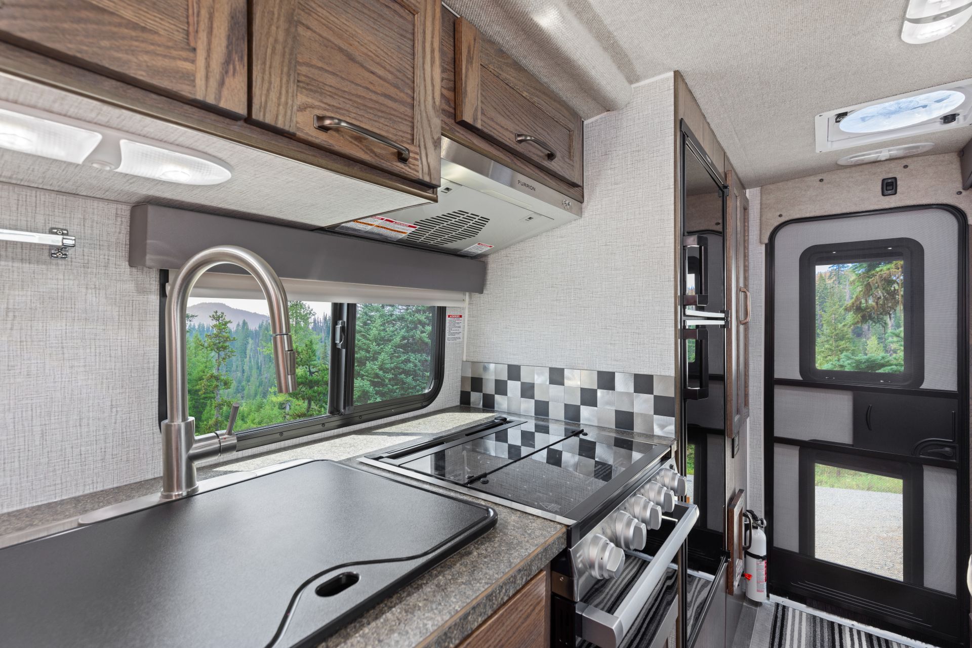 Keuken van een Maxi Travel 4x4 Camper met gootsteen, fornuis, houten kastjes en geblokte achterwand