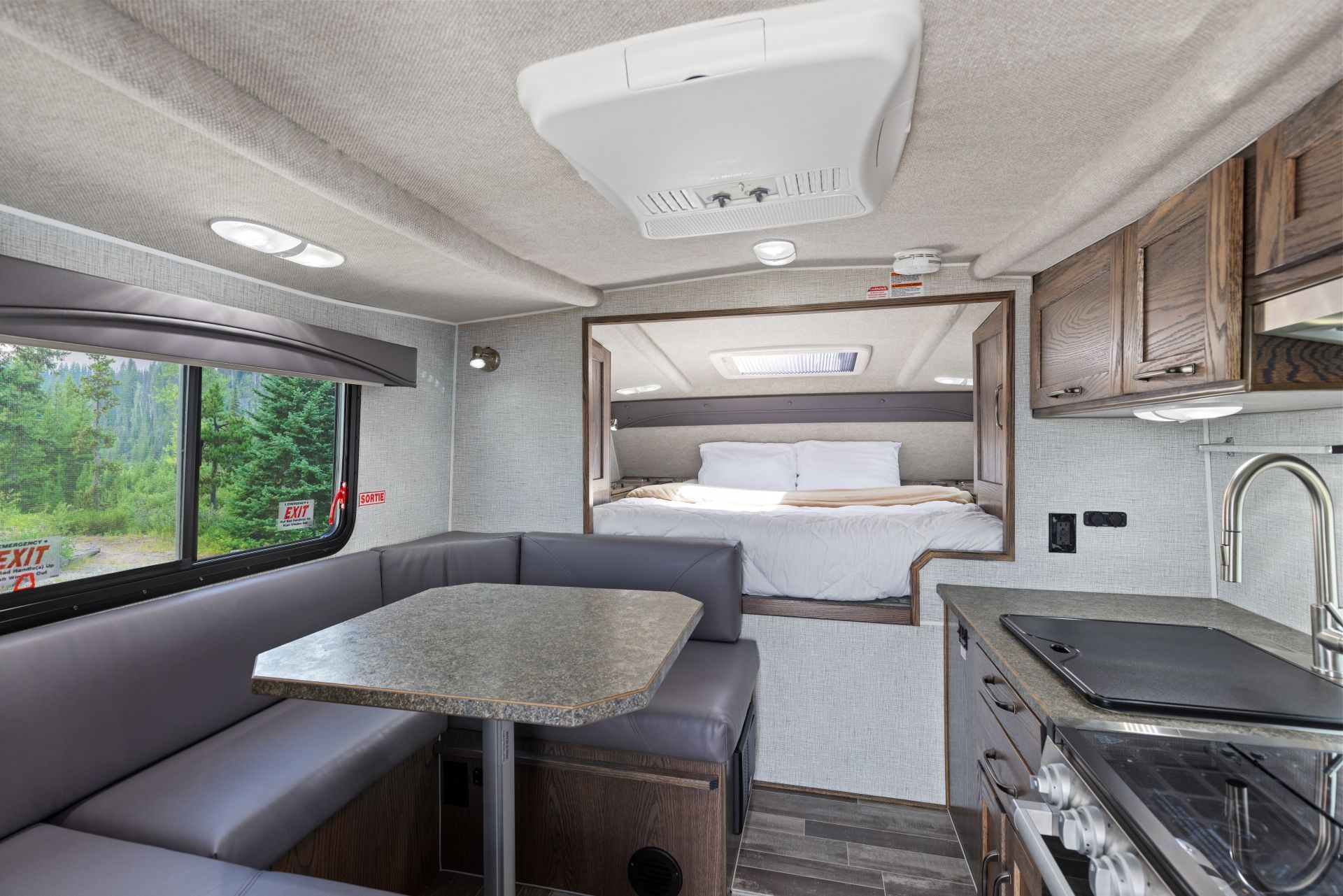 Compact interieur van een Maxi Travel 4x4 Camper met dinette, kitchenette en slaapgedeelte in neutrale tinten