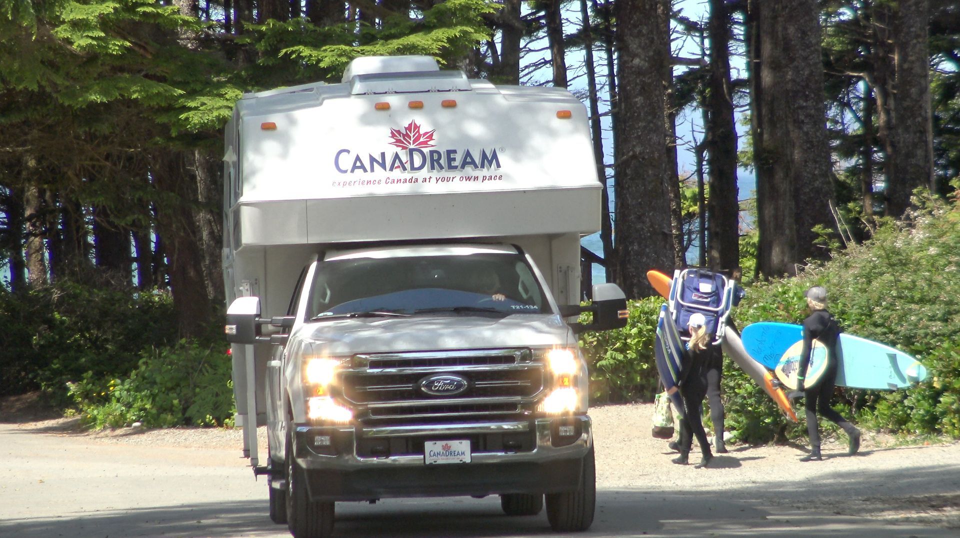 Een Canadream-camper staat geparkeerd langs een bosrijke weg,