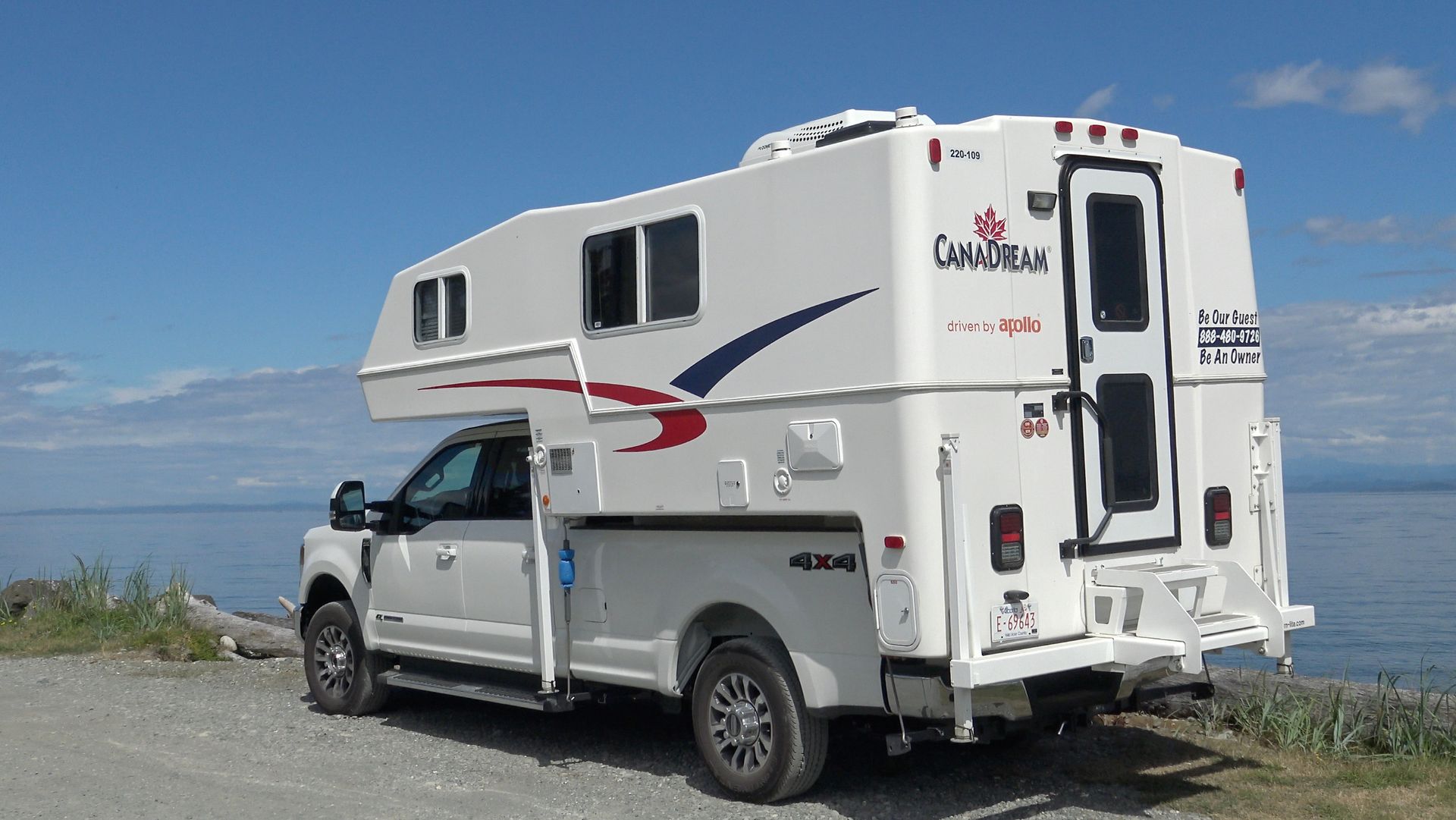 Maxi Travel 4x4 Camper geparkeerd op een grindweg aan het water onder een blauwe hemel
