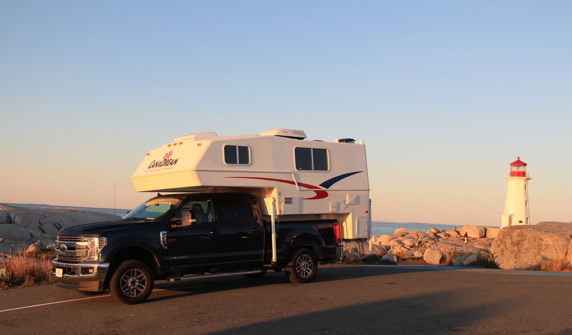 Maxi Travel 4x4 Camper naast de vuurtoren van Peggy's Cove bij zonsondergang