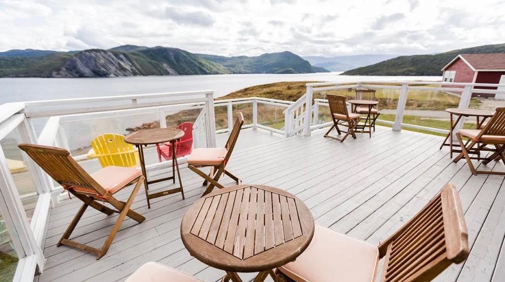 Terras met uitzicht op het meer, met houten stoelen en tafels, en uitzicht op de bergen en het water.
