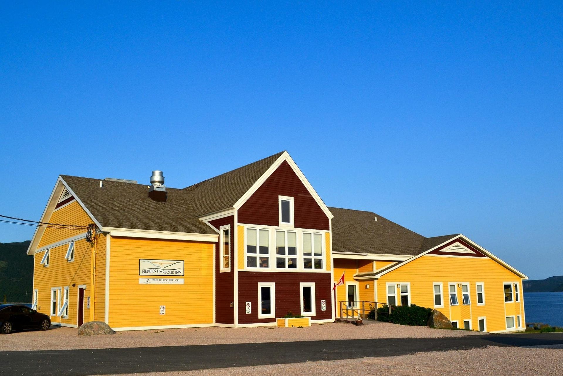 Geel en rood gebouw met witte accenten tegen een helderblauwe hemel.