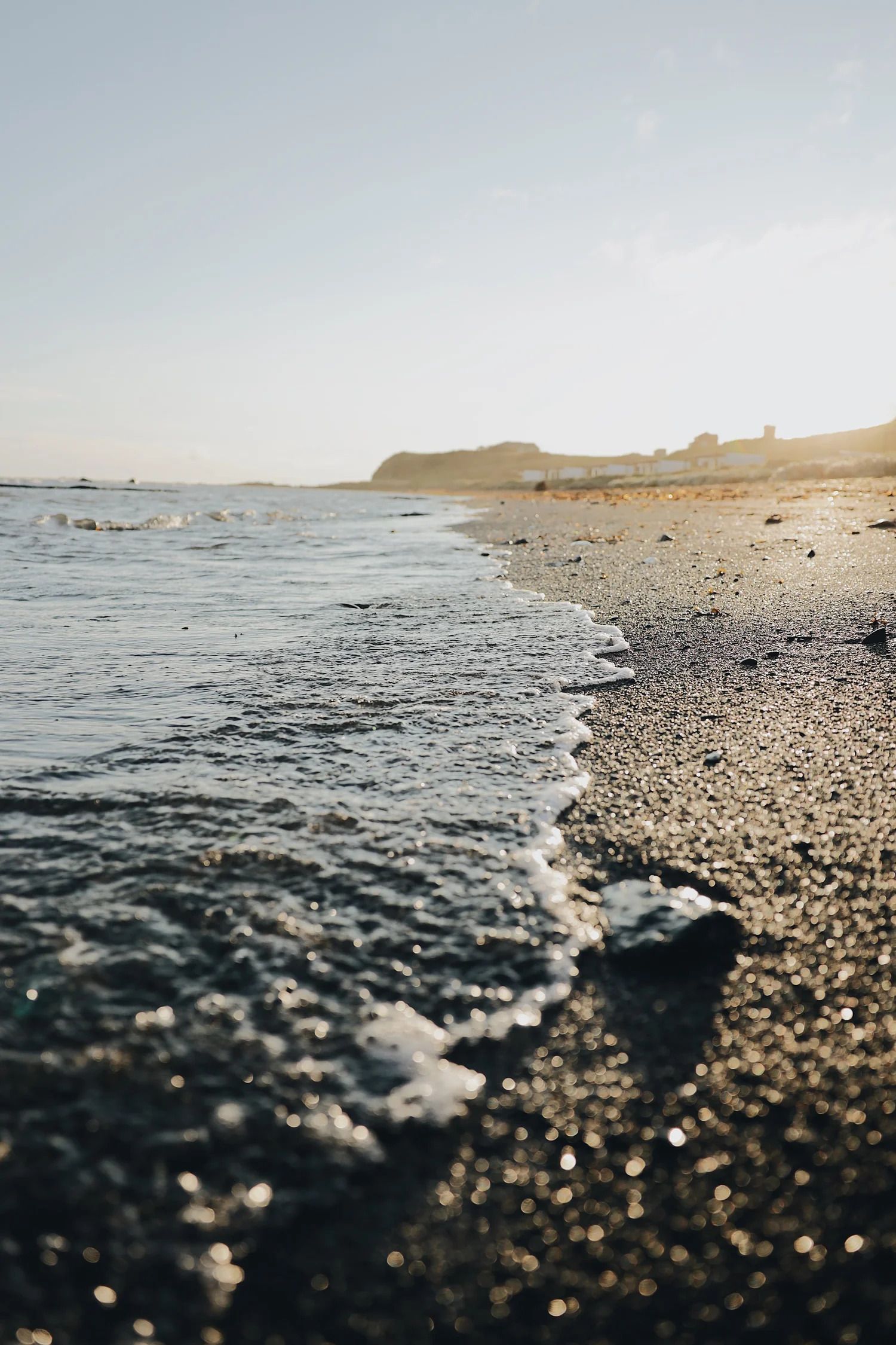 Een kiezelstrand met zachte golven die bij zonsondergang op het strand aanspoelen.