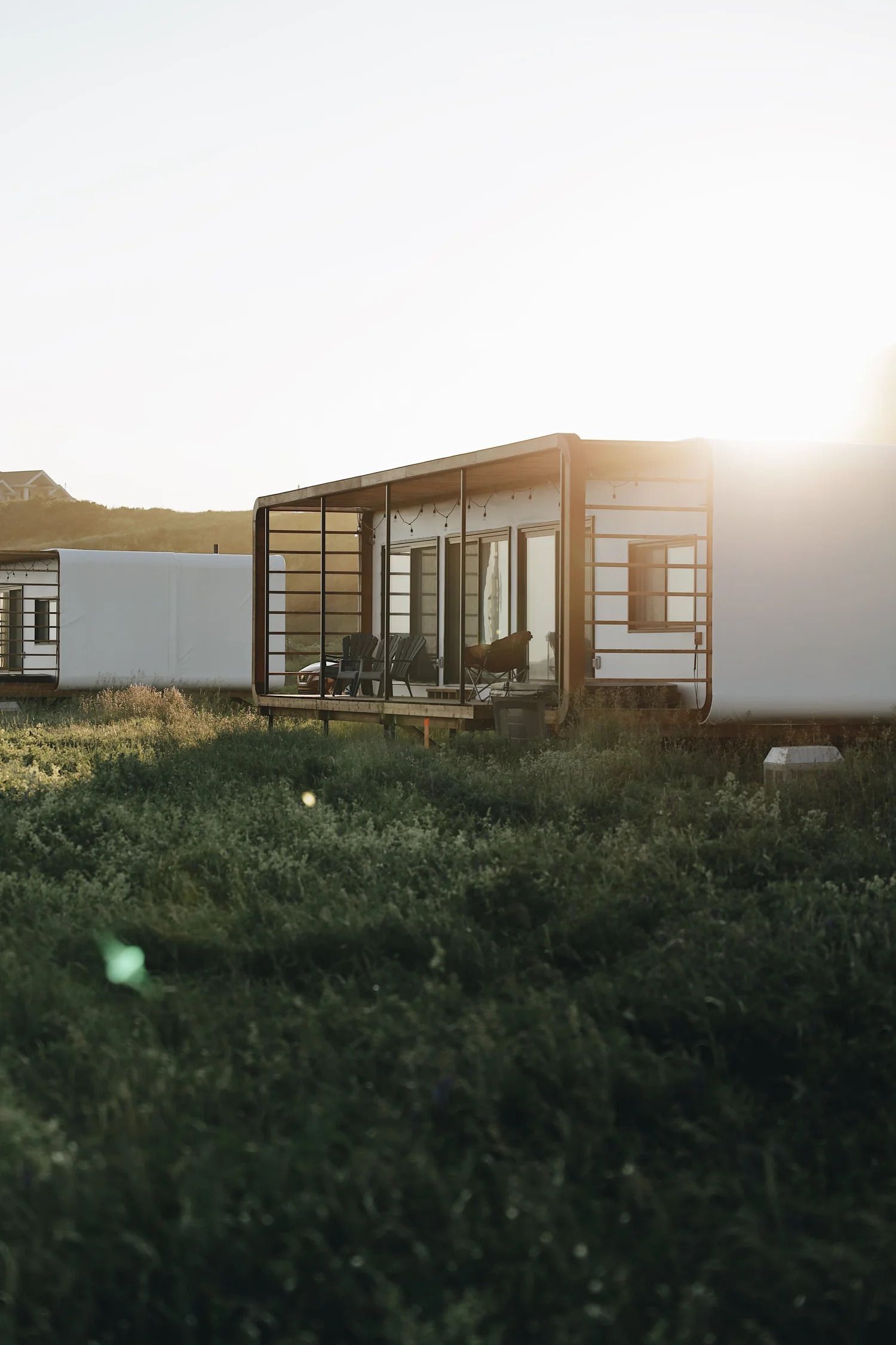 Moderne modulaire woning met grote ramen in een grasveld bij zonsondergang.